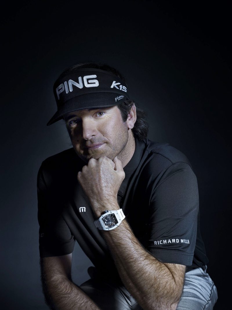 A man wearing a golf cap with ING K1S print, black top with Richard Mille, and white wrist watch