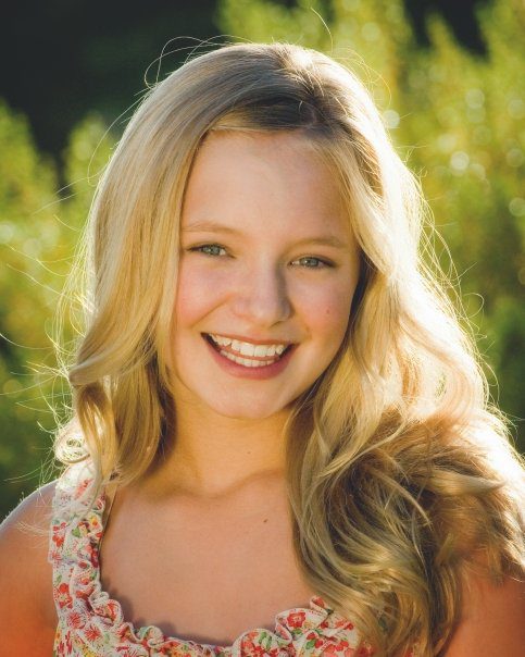 A young woman with long blonde hair smiles.