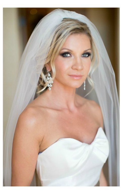 A bride with blonde hair, wearing a veil and a tube wedding dress