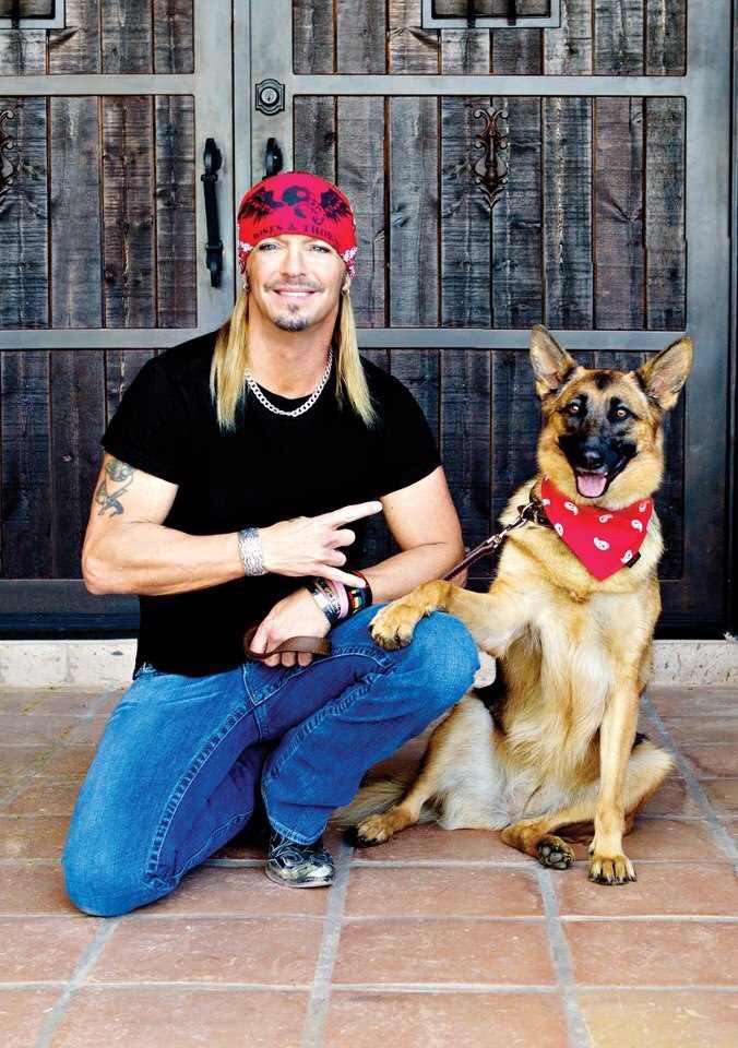 A man with long, blonde hair, wearing red cap and a dog wearing a red scarf
