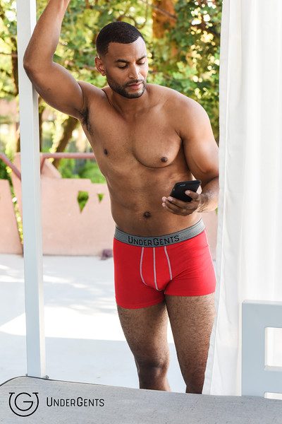 A man wearing red undergarment while holding his phone